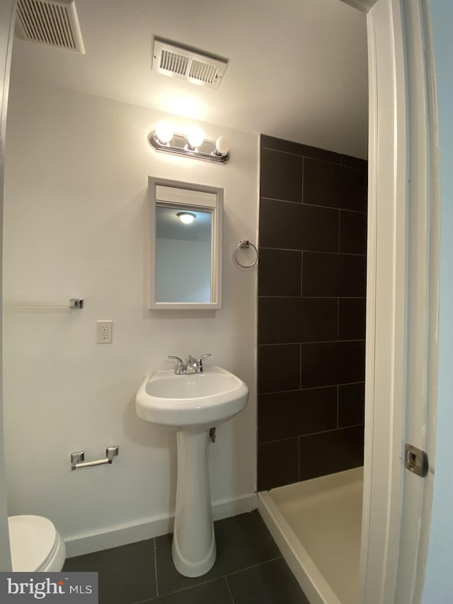 bathroom featuring tile patterned flooring, toilet, and a shower