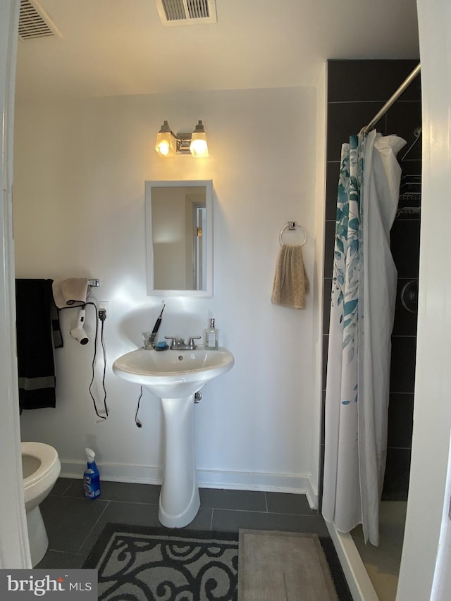 bathroom featuring tile patterned flooring, toilet, and walk in shower