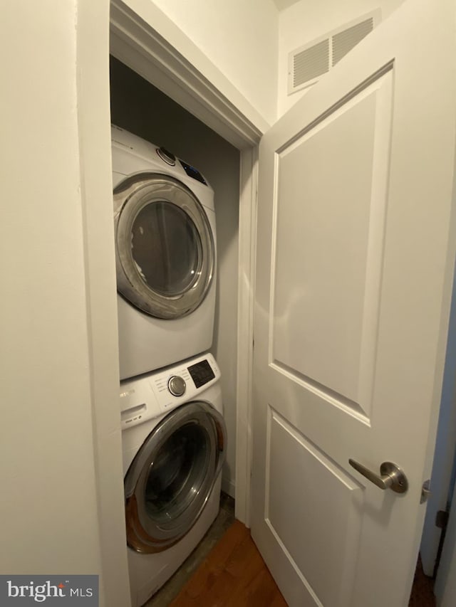 clothes washing area with dark hardwood / wood-style flooring and stacked washing maching and dryer