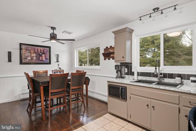 kitchen featuring light tile patterned floors, a baseboard radiator, ceiling fan, and sink