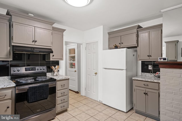 kitchen featuring backsplash, light tile patterned floors, gray cabinets, white fridge, and stainless steel range with electric cooktop