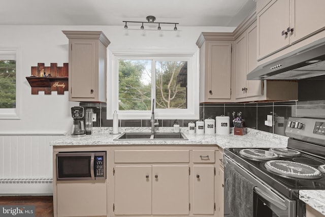 kitchen with decorative backsplash, light stone counters, stainless steel appliances, sink, and cream cabinets