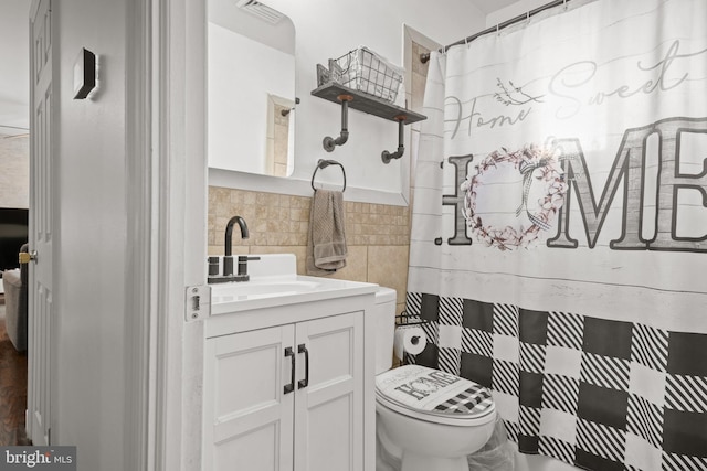 bathroom with vanity, backsplash, and toilet