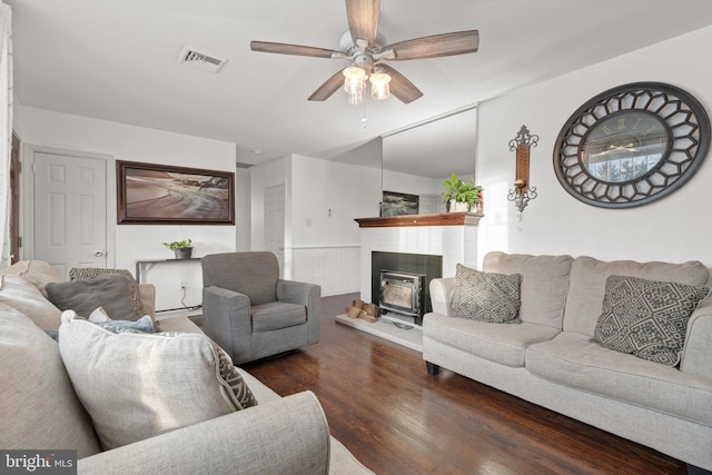 living room with a wood stove, ceiling fan, and dark hardwood / wood-style flooring