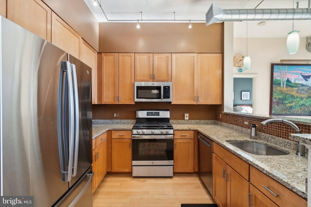 kitchen featuring sink, light stone counters, pendant lighting, track lighting, and appliances with stainless steel finishes