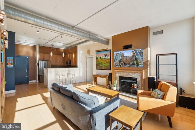 living room featuring track lighting, a premium fireplace, and light hardwood / wood-style flooring