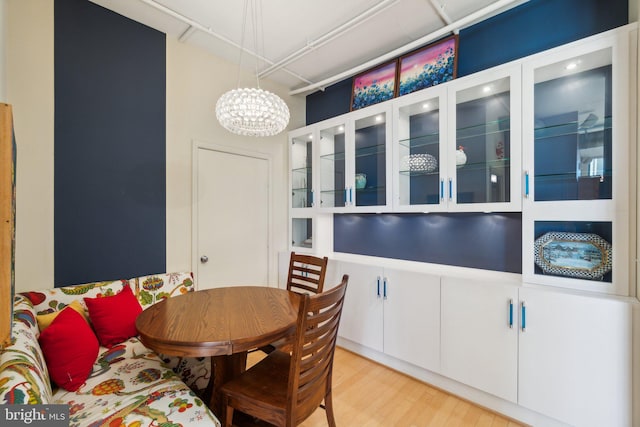 dining room with light wood-type flooring and an inviting chandelier