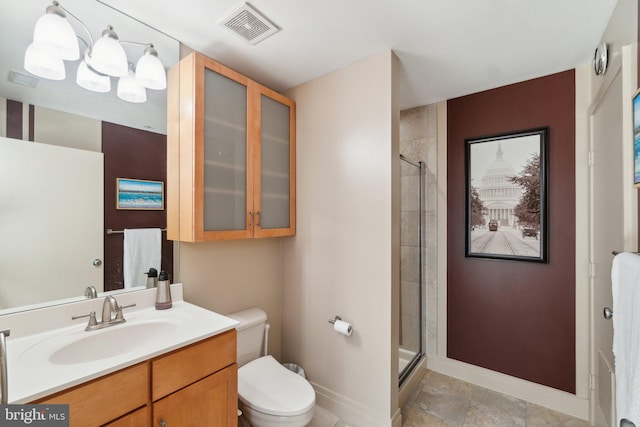 bathroom with a chandelier, vanity, toilet, and a shower with door