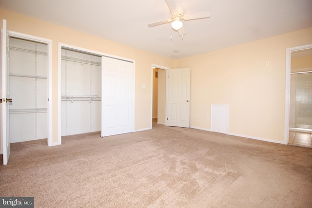 unfurnished bedroom with multiple closets, ceiling fan, ensuite bathroom, and light carpet