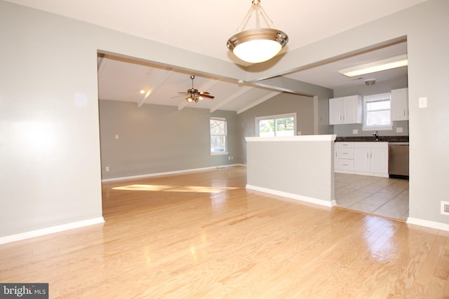 interior space with light wood-type flooring, vaulted ceiling with beams, ceiling fan, and sink