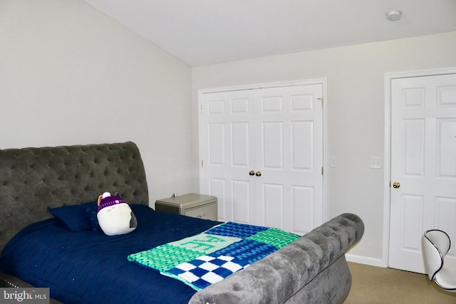 carpeted bedroom with a closet and lofted ceiling