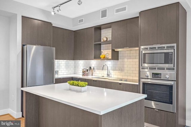 kitchen with dark brown cabinetry, decorative backsplash, sink, and appliances with stainless steel finishes