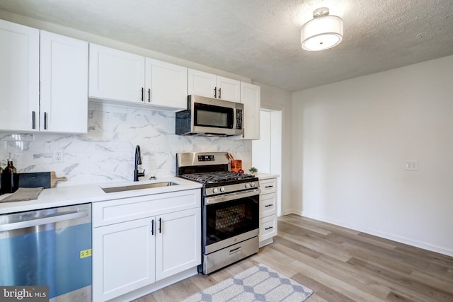 kitchen featuring a sink, stainless steel appliances, light wood-style flooring, and white cabinets