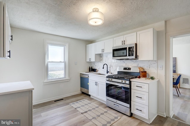 kitchen with visible vents, a sink, stainless steel appliances, light countertops, and backsplash