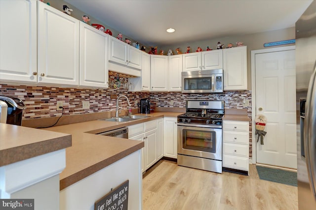 kitchen with white cabinetry, sink, stainless steel appliances, backsplash, and light hardwood / wood-style floors