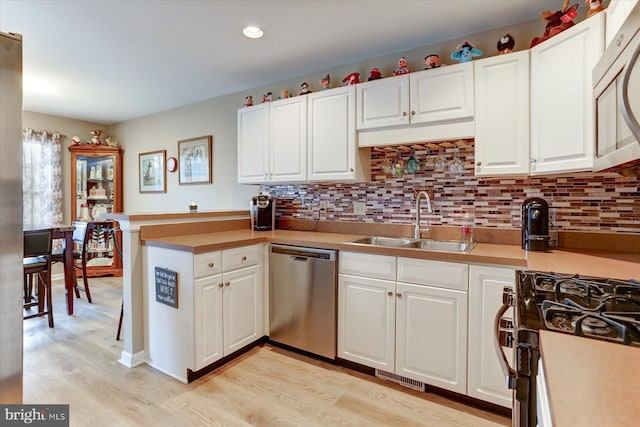 kitchen featuring kitchen peninsula, sink, white cabinets, and appliances with stainless steel finishes