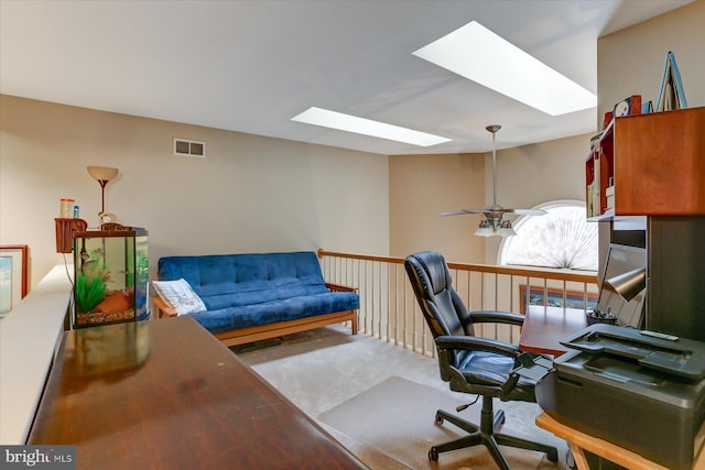 home office featuring a skylight, ceiling fan, and carpet