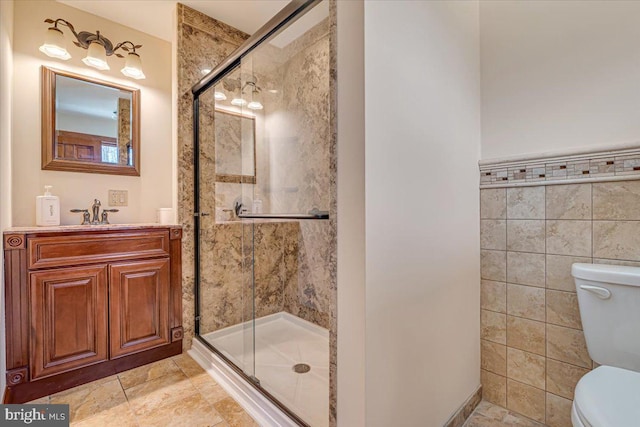 bathroom with an enclosed shower, vanity, toilet, and tile walls