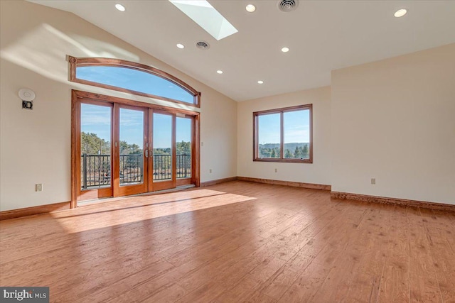 unfurnished living room with light hardwood / wood-style floors, french doors, high vaulted ceiling, and a skylight