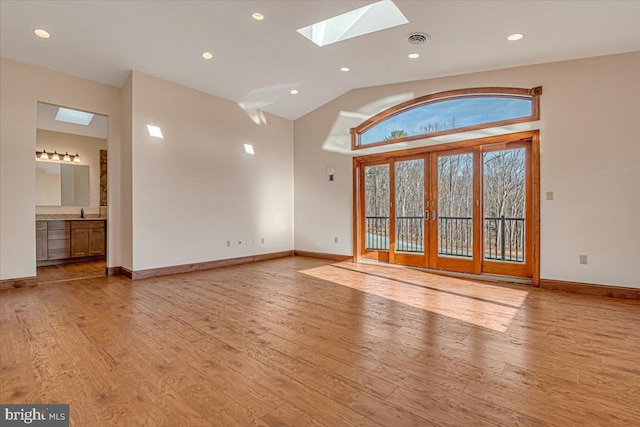 interior space with french doors, light hardwood / wood-style flooring, lofted ceiling with skylight, and sink