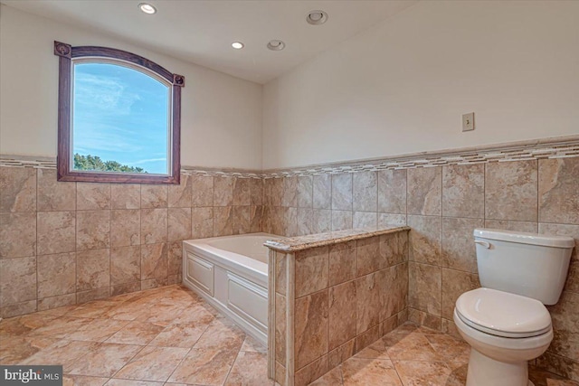 bathroom featuring a tub to relax in, tile walls, and toilet