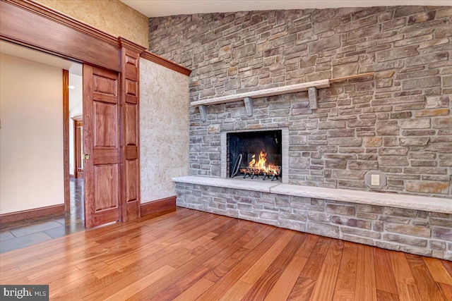 unfurnished living room featuring a stone fireplace, wood-type flooring, and lofted ceiling