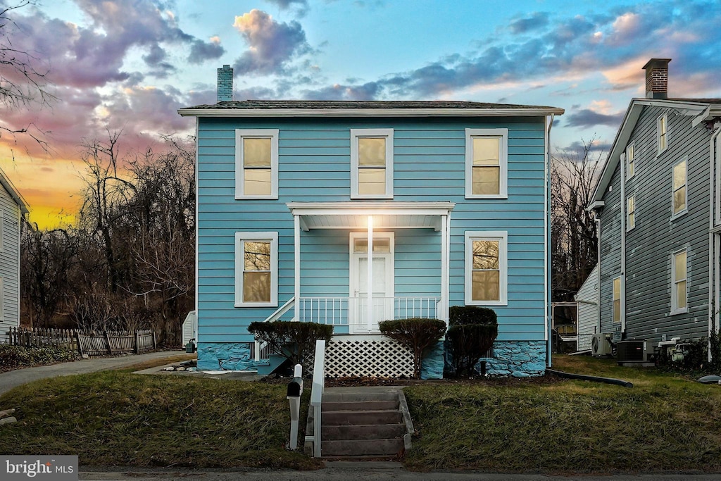 view of front of house with cooling unit and a yard