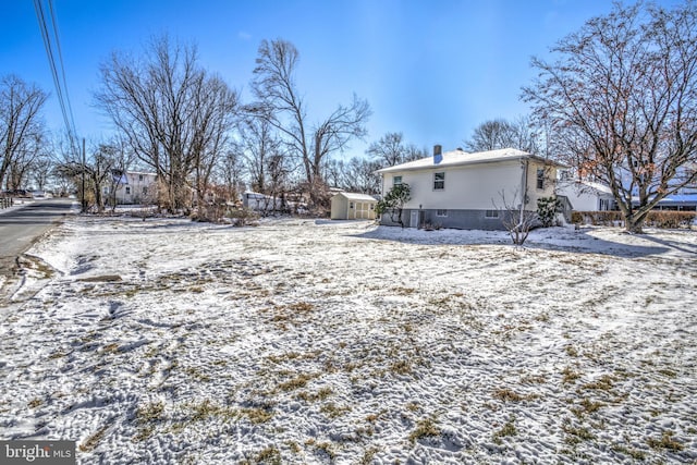 snowy yard featuring a storage unit