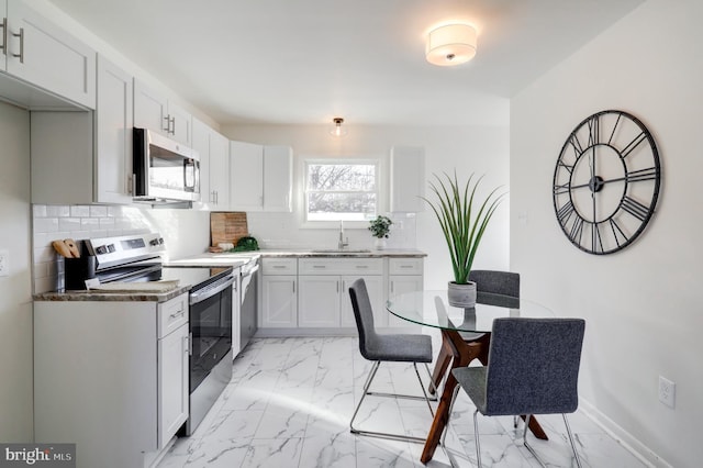 kitchen featuring white cabinets, stainless steel appliances, tasteful backsplash, and sink