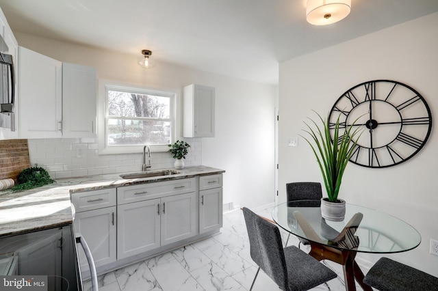 kitchen featuring decorative backsplash, sink, white cabinets, and light stone countertops