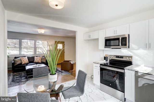 kitchen with white cabinets, decorative backsplash, stainless steel appliances, and light stone counters