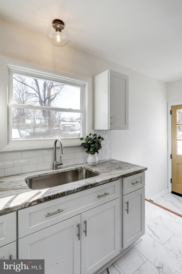 kitchen with stone countertops, tasteful backsplash, and sink