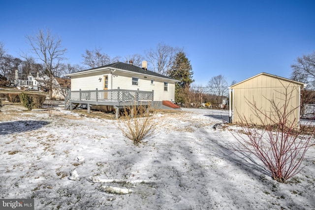 snow covered rear of property with a deck