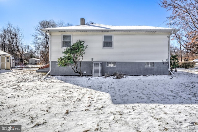 snow covered house featuring central air condition unit