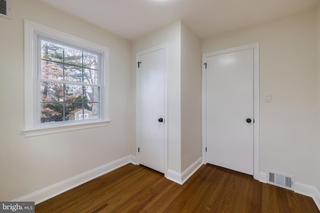 unfurnished bedroom featuring dark hardwood / wood-style floors and a closet