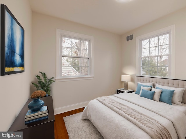 bedroom featuring dark hardwood / wood-style flooring and multiple windows