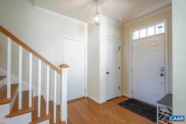 foyer entrance with crown molding, light wood-type flooring, and an inviting chandelier