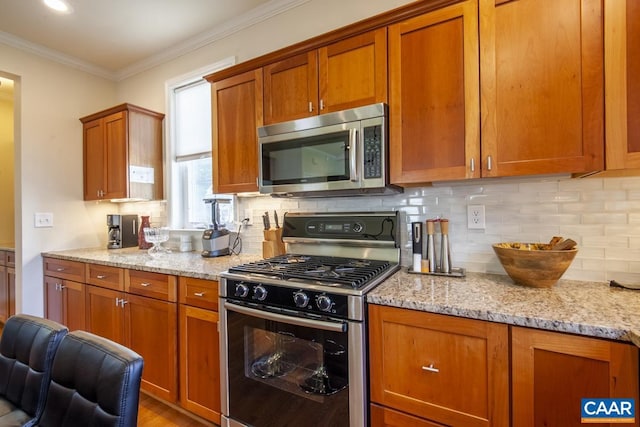 kitchen with decorative backsplash, light stone countertops, stainless steel appliances, and ornamental molding