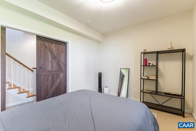 bedroom featuring a barn door and light colored carpet