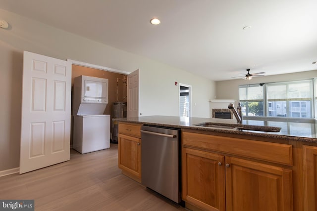 kitchen featuring ceiling fan, sink, light hardwood / wood-style flooring, stainless steel dishwasher, and stacked washer / dryer