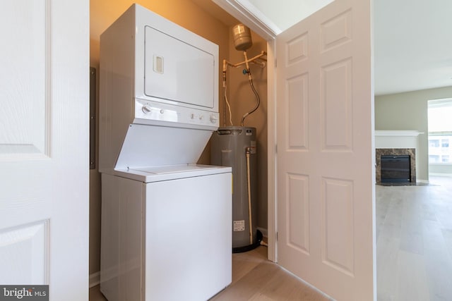 laundry area featuring light hardwood / wood-style floors, stacked washer / dryer, and water heater