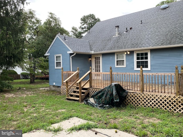 back of property with a deck and a lawn