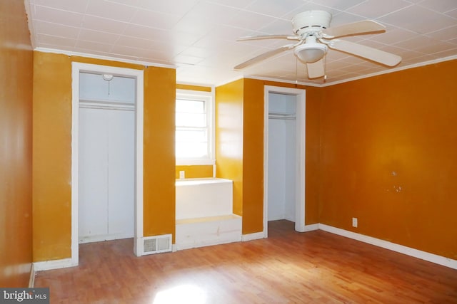 unfurnished bedroom with ceiling fan, ornamental molding, and hardwood / wood-style flooring