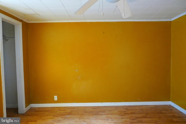 empty room with ceiling fan, wood-type flooring, and ornamental molding