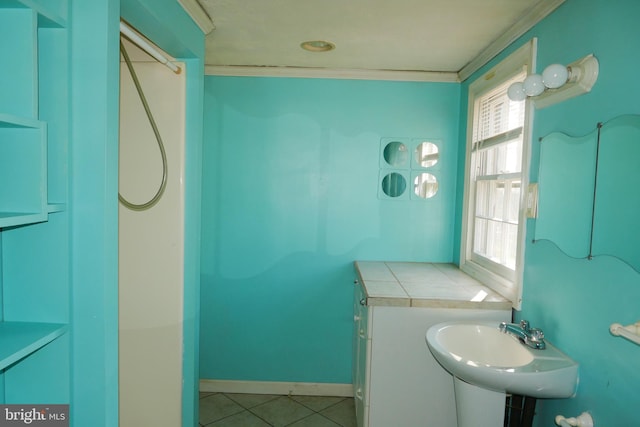 bathroom with tile patterned flooring, crown molding, and sink