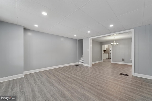 basement with hardwood / wood-style floors, a paneled ceiling, and stainless steel fridge