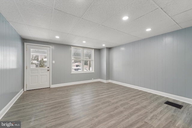 spare room featuring a drop ceiling and hardwood / wood-style flooring