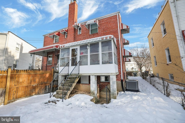 snow covered back of property featuring central AC