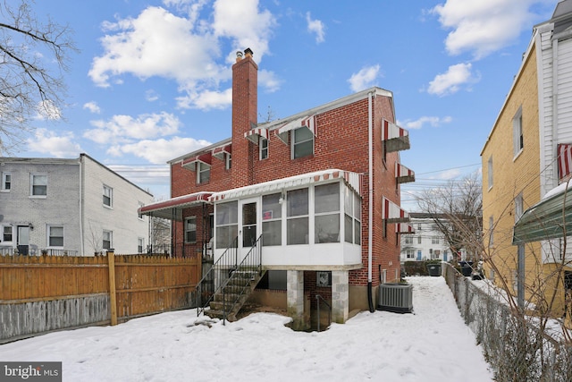 snow covered property with cooling unit and a sunroom