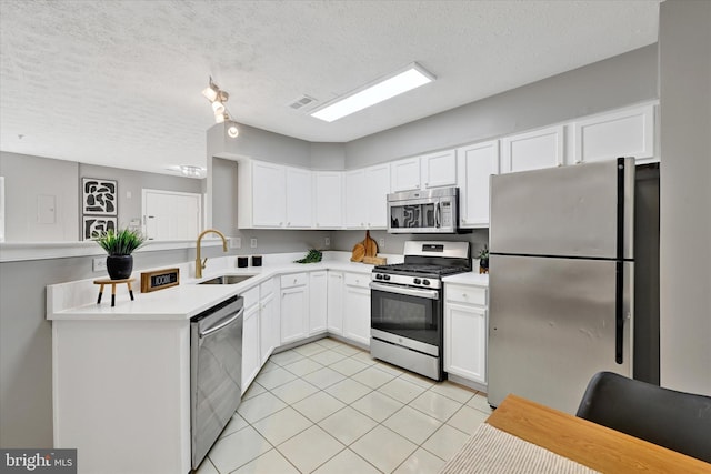 kitchen with sink, a textured ceiling, light tile patterned flooring, white cabinetry, and stainless steel appliances